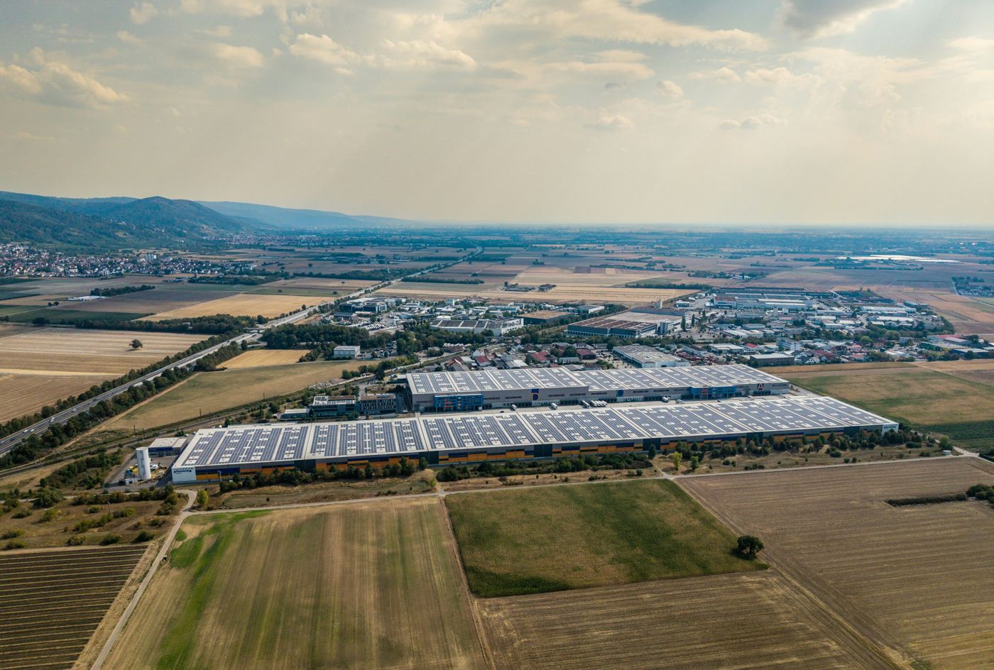 Vista aérea de uma zona industrial com painéis solares nos telhados